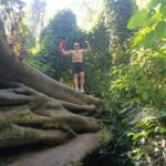 Young travelers exploring the inside of a naturally hollow tree in the Tamblingan forest.