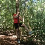 Adventurous traveler swinging from a tree like Tarzan in the wild Tamblingan forest during a guided Twin Lake Jungle Trekking adventure with a local guide